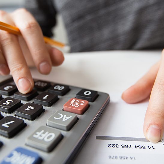 Closeup of accountant counting on calculator and working with table